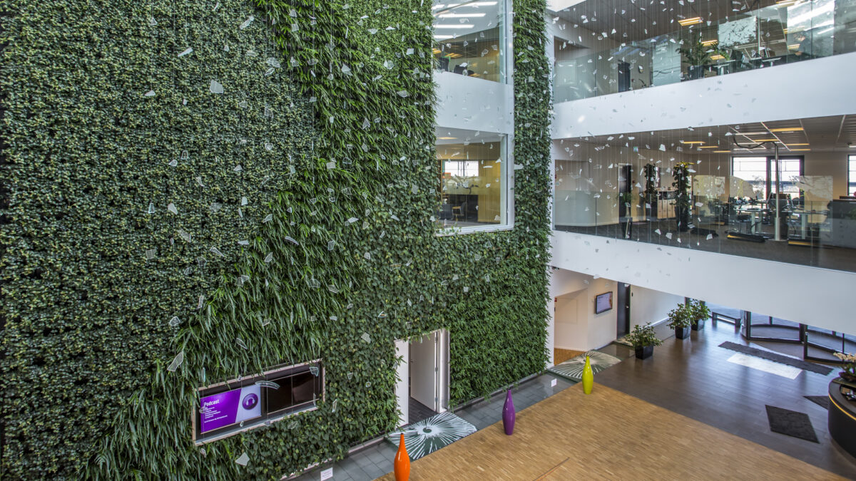 Projekter Krifa 3 Projekter. Receptions område i 3 etager med kig til kontorer. Stor væg med grønne planter.